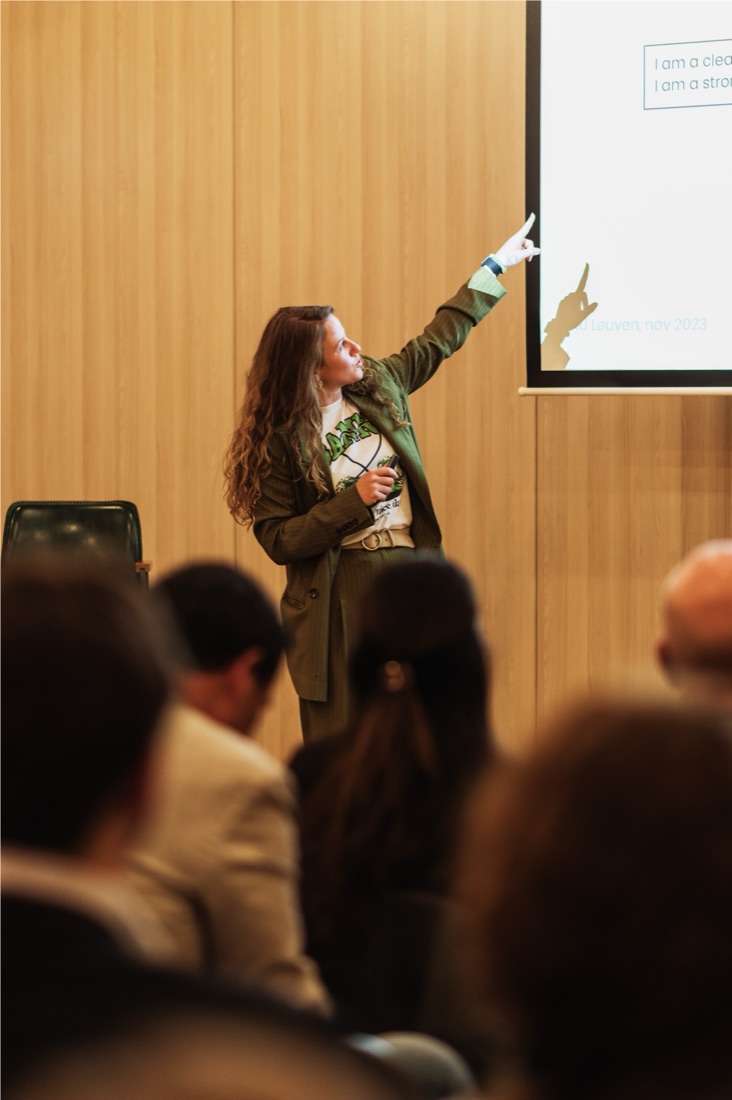 Ilona wijst naar het scherm voor een volle zaal